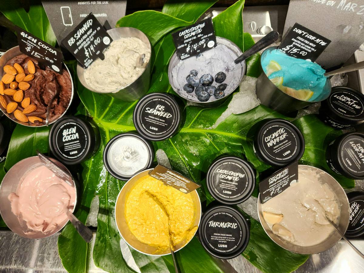 natural lotion in a reusable glass jar beside fresh chamomile and aloe vera leaves